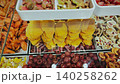 Assorted dried fruits like apricots, figs, and mango slices are beautifully arranged in a glass display case at a market, highlighting their vibrant colors and textures 140258262