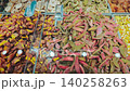 Vibrant display of assorted dried fruits and snacks in a market, showcasing colorful orange, yellow, and red varieties in clear containers with a scoop 140258263