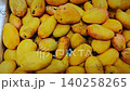 Yellow mangoes of different sizes and shapes are arranged in a white container, highlighting their freshness and vibrant color in a market environment 140258265