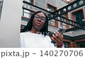 Woman checks phone in modern urban space on a sunny day with interesting architecture around 140270706