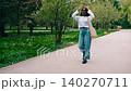Walking through a park with green trees and flowers during the day with a person dressed casually and enjoying the outdoors 140270711