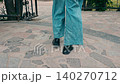 Walking through a stone pathway in a park during a sunny day while wearing casual clothing 140270712