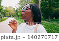 Woman blows on dandelion seeds in park on a sunny day enjoying nature and fresh air 140270717