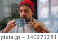 A man enjoying a fresh croissant and coffee for breakfast. Slow motion 140271281