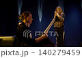 Aspiring actors rehearsing dramatic script on dimly lit theater stage, seated and standing 140279459