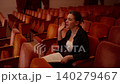 Young woman rehearsing lines alone in an empty theater auditorium, practicing expressive gestures 140279467