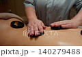 Relaxing hot stone back massage therapy with smooth heated stones placed along the spine and 140279488