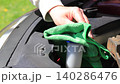 Man hand cleaning car engine bay with microfiber cloth, wiping dust under hood outdoors, car maintenance and care, checking and refilling windshield washer fluid, auto service concept, vehicle 140286476