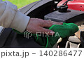 Man hand cleaning car engine bay with microfiber cloth, wiping dust under hood outdoors, car maintenance and care, checking and refilling windshield washer fluid, auto service concept, vehicle 140286477