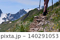 Hiker walking with trekking poles on a rocky alpine trail 140291053