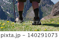 Alpine boot in a wildflower meadow with rocky mountain peaks behind 140291073