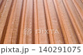 Close oblique view of weathered corrugated metal roof panel with diagonal ribs 140291075