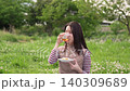 A woman drinking tea at a picnic. 140309689