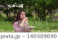 A woman drinking tea while having a picnic meal. 140309690