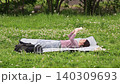 A woman reading a book while lying on a picnic blanket outdoors. 140309693