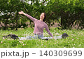 A fixed shot of a woman stretching amidst fresh greenery. 140309699