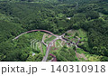 Aerial drone shot beginning above a winding forest road before tilting upward to reveal the expansive mountain landscape surrounding Odawara in Kanagawa Prefecture, Japan. 140310918