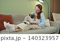 Woman Writing in Notebook with Pug on Sofa 140323957