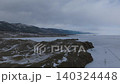 Winter aerial view of frozen Lake Baikal shoreline and mountains under clouds 140324448