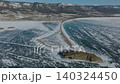 Aerial winter view of Lake Baikal ice and shoreline road near mountains, Russia 140324450