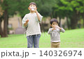 A brother and sister rehydrating in the park 140326974