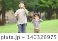 A brother and sister rehydrating in the park 140326975