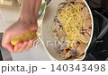 Asian female influencer cooking vlog video using smartphone showing spaghetti alle vongole recipe with fresh clams parsley and lemon juice in modern kitchen atmosphere squeezing lemon over clam pasta 140343498
