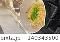 Cooking pasta and noodle with green vegetables white pot, stirring with green spatula stovetop kitchen, home cooking scene showing spaghetti alle vongole recipe, fresh parsley, clams, and joyful 140343500