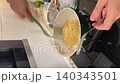 Asian female influencer cooking vlog video using smartphone showing spaghetti alle vongole recipe in modern kitchen with fresh ingredients joyful expression and marble countertop background 140343501