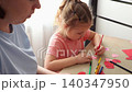 Caucasian woman helping her young child create colorful postcards and drawings during an educational activity. Child development and creative parenting concept. Close up. 140347950