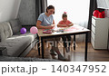 Caring mother and preschool daughter working on creative craft activities while playing with balloons at home. Childhood development and family relationship concept. Wide shot. 140347952