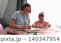 Mother and daughter spending quality time making handmade decorations and blowing up balloons indoors. Education, creativity, and positive parenting concept 140347954