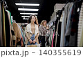 Customer shopping in modern retail clothing store. Diverse people in fashionable shop, choosing stylish clothes, colorful brand designs, quality sustainable materials 140355619