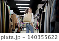 Beautiful Caucasian woman happy with her purchases. Attractive woman spinning around with paper bags full of purchased clothes in shopping mall 140355622