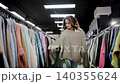 A woman chooses a warm sweater from two variants. Winter clothing store. A woman chooses warm clothes with interest. Lady shopaholic. Winter clothing store 140355624