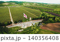 Georgian national flag waving over a rural vineyard landscape 140356408