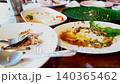 Empty white and green dinner plates with sauce stains and food scraps after a meal on a wooden restaurant table. Concept of finished dinner, messy dishes, and food waste in close up view. 140365462