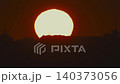 Sunset over the city skyline showing bright orange sun sinking behind the buildings 140373056
