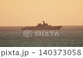 Large naval ship sails on open water during sunset near coastline 140373058