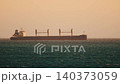 Cargo ship sails on the ocean during sunset near the coast 140373059