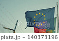 European flag waves in the wind near a border with a glimpse of another country s flag and a fence in the background 140373196