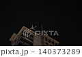 An Airplane Flying Low Over Modern Skyscrapers in the Dark Night Sky 140373289