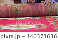 Close up of student hands rolling a large red carpet during event cleanup or room organization. 140373636