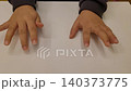 A Child's Hands Wiggling and Tapping Their Fingers on a White Table 140373775