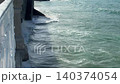 Ocean Waves Crashing Against Concrete Pier Column View from Embankment Railing 140374054