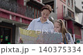 Portrait of woman with little daughter reads map against old buildings. Happy family of mother and girl visits foreign country on holiday. Travel with children 140375334