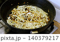 Thinly sliced onions are fried in hot oil. Cooking chopped vegetables in a frying pan. Chopped onions are fried on the stove. Close-up: frying, browning, seasoning. Food preparation. Cooking. 140379217