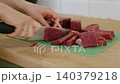 A housewife cuts beef on a cutting board. Close-up of hands with a knife cutting meat. Healthy eating. Preparing a raw beef steak for a family dinner. Handling raw meat. Cooking. Homemade food. 140379218