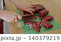 A housewife cuts beef on a cutting board. Close-up of hands with a knife cutting meat. Healthy eating. Preparing a raw beef steak for a family dinner. Handling raw meat. Cooking. Homemade food. 140379219