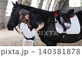 Young woman bonding with black horse in stable 140381878